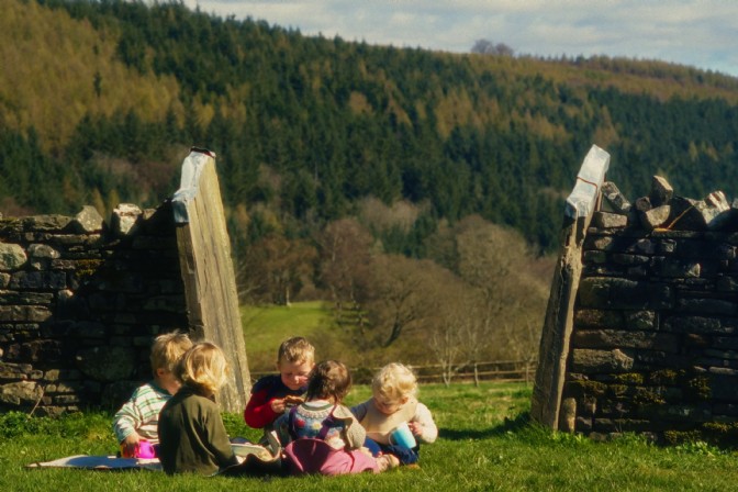 Children sat outside with the mountains behind