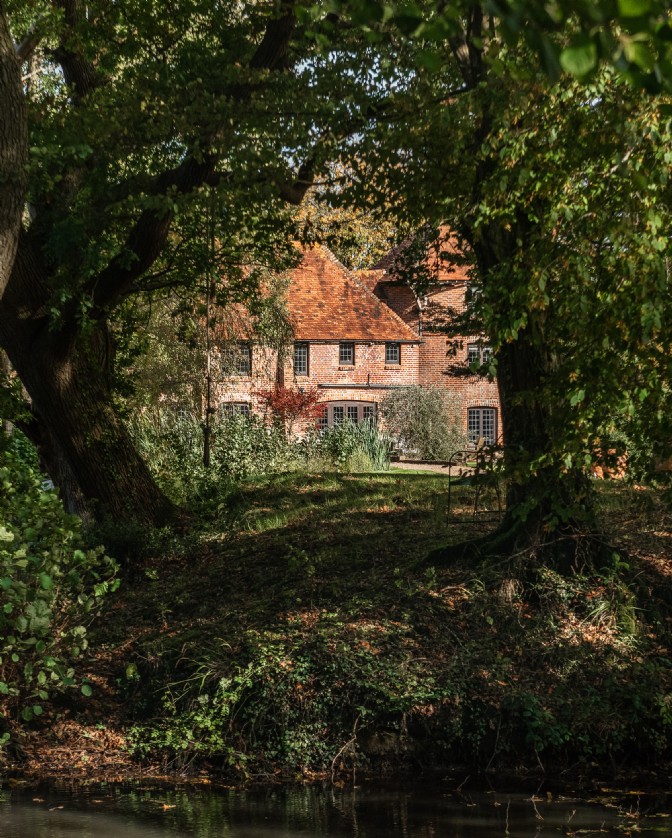 Roserai: a red oast house-turned-home can be seen through the trees