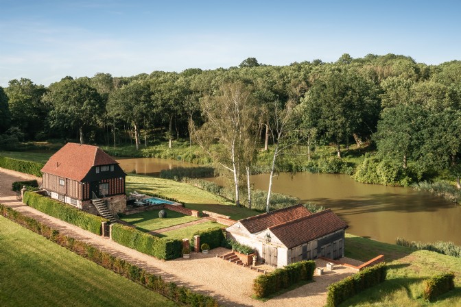 Woods in the background and a beautiful barn in landscaped grounds with a pool called Fawn Wood in High Weald, East Sussex