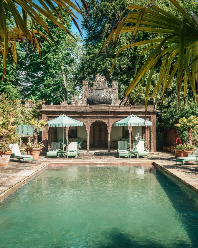 An Indian pool surrounded by palms and under golden light, Castle India is one of the storybook homes in Britain