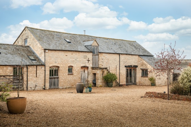 An old converted farmhouse beneath a blue sky in the Cotswolds