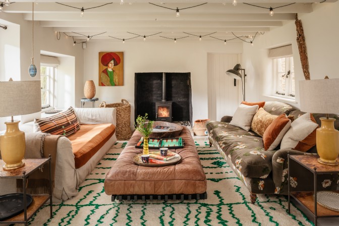 A living room with two sofas, plush rug, fireplace and festoon lighting