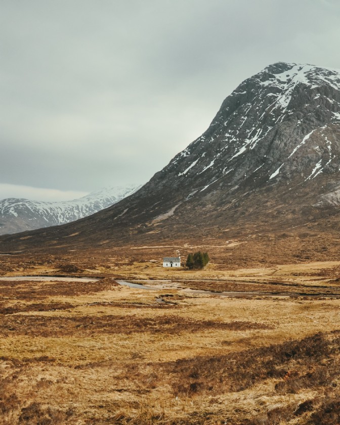 A small white house in a winter mountain landscape on Isle of Skye in the Hebridea
