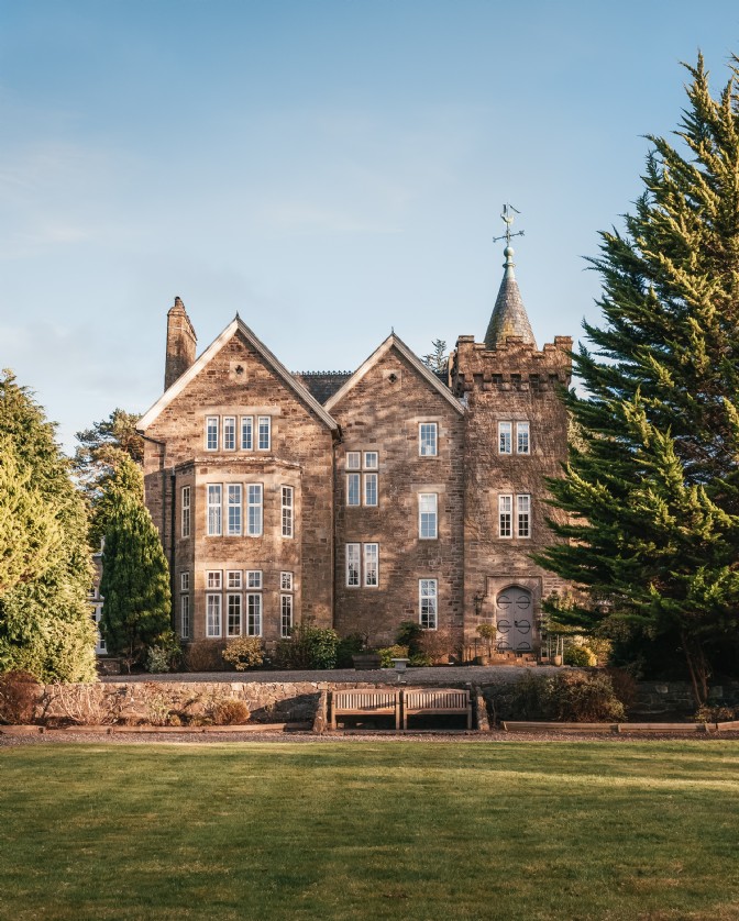 An impressive country house with a castellated tower and many rectangular sash windows