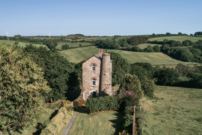 A fairytale stone tower surrounded by green fields and trees