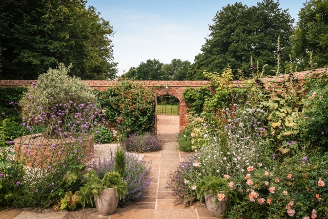 An image of a walled garden, filled with roses and herbs