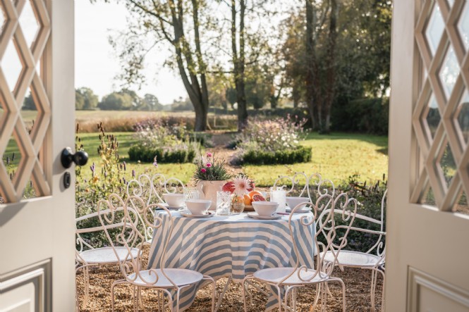Double doors open from the living room to the stone garden, enveloped in flowers