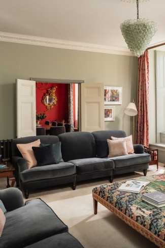 Sunlight pours through the sage green sitting room